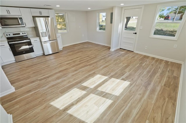 kitchen featuring white cabinetry, light hardwood / wood-style floors, appliances with stainless steel finishes, and backsplash