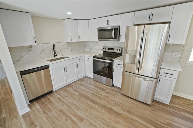 kitchen with sink, white cabinets, light hardwood / wood-style flooring, and stainless steel appliances