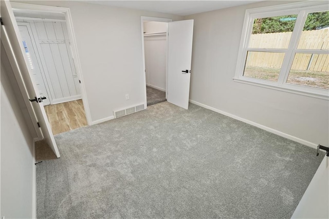 unfurnished bedroom featuring a closet, light carpet, and a spacious closet