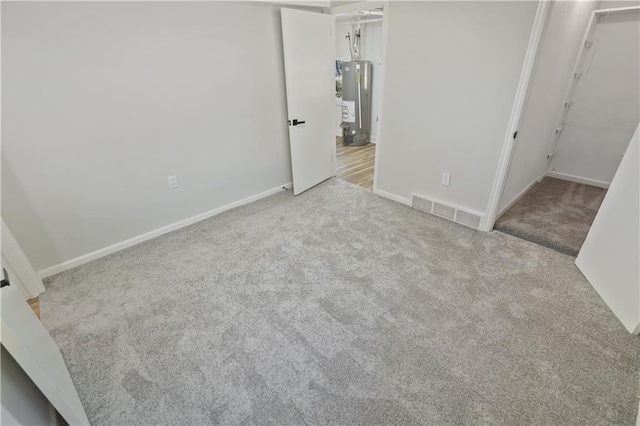 unfurnished bedroom featuring water heater, light carpet, and a closet