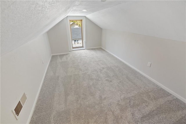 bonus room featuring light carpet, a textured ceiling, and vaulted ceiling