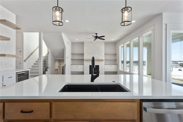 kitchen with pendant lighting, a kitchen island with sink, sink, and dishwasher