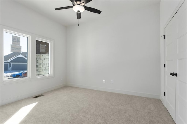 empty room with ceiling fan and light colored carpet