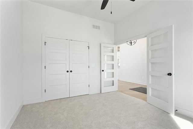 unfurnished bedroom featuring light carpet, a closet, and ceiling fan