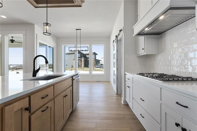 kitchen featuring white cabinetry, a barn door, custom range hood, and sink