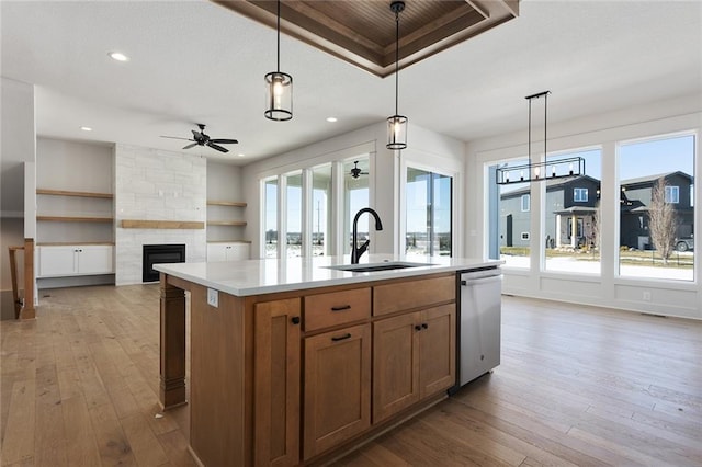 kitchen featuring a kitchen island with sink, sink, decorative light fixtures, and stainless steel dishwasher