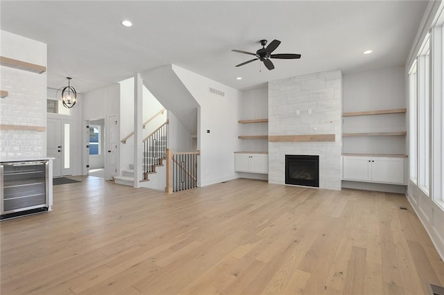 unfurnished living room with a tiled fireplace, plenty of natural light, and light wood-type flooring