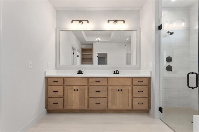 bathroom featuring a raised ceiling, vanity, tile patterned flooring, and a shower with shower door