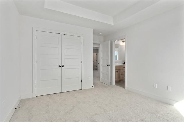 unfurnished bedroom with connected bathroom, light colored carpet, and a closet