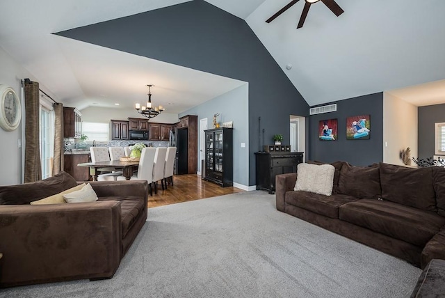 living room with lofted ceiling, ceiling fan with notable chandelier, and light hardwood / wood-style floors