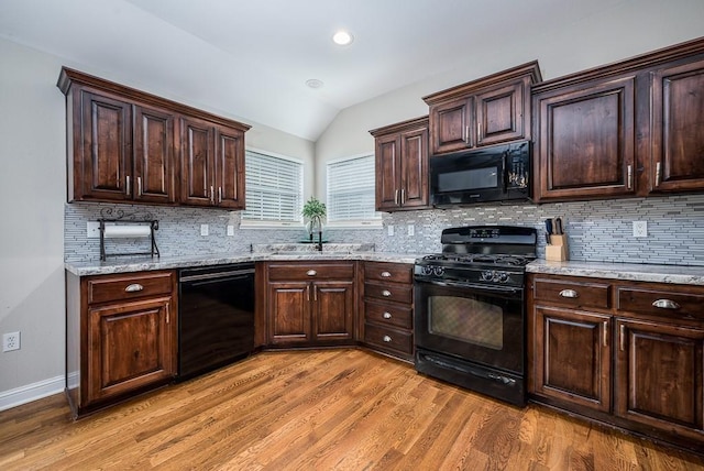 kitchen featuring black appliances, sink, light wood-type flooring, and decorative backsplash