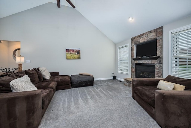 carpeted living room featuring ceiling fan, beamed ceiling, plenty of natural light, and a fireplace