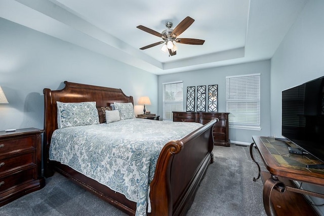 carpeted bedroom featuring ceiling fan and a tray ceiling