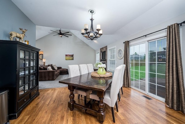 dining room featuring lofted ceiling, wood-type flooring, and ceiling fan with notable chandelier