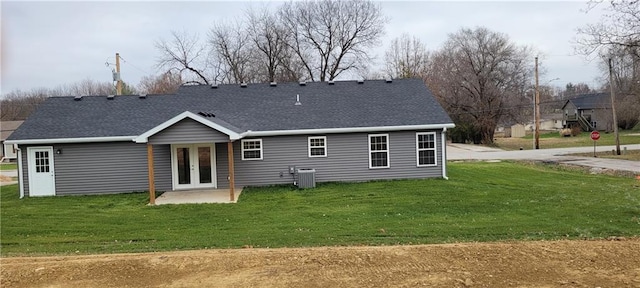 rear view of property featuring cooling unit and a lawn