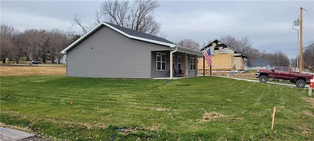 view of side of home featuring a lawn and covered porch