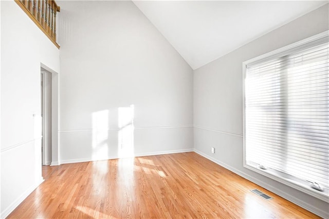 empty room with light hardwood / wood-style floors and high vaulted ceiling