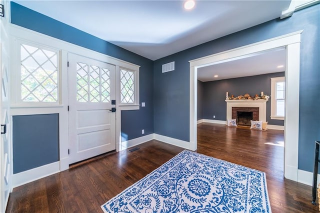 entryway with a brick fireplace, plenty of natural light, and dark hardwood / wood-style flooring