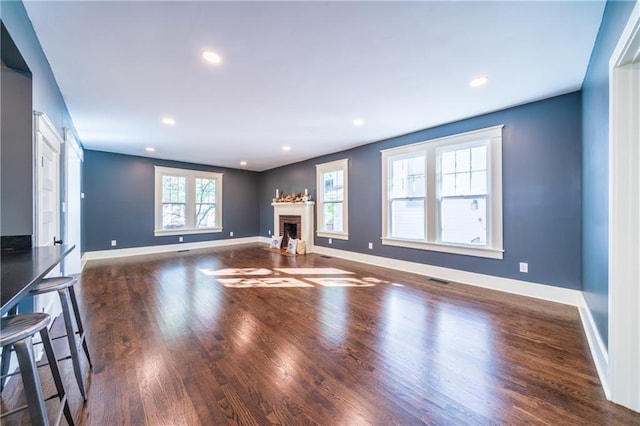 unfurnished living room with a brick fireplace and dark hardwood / wood-style floors