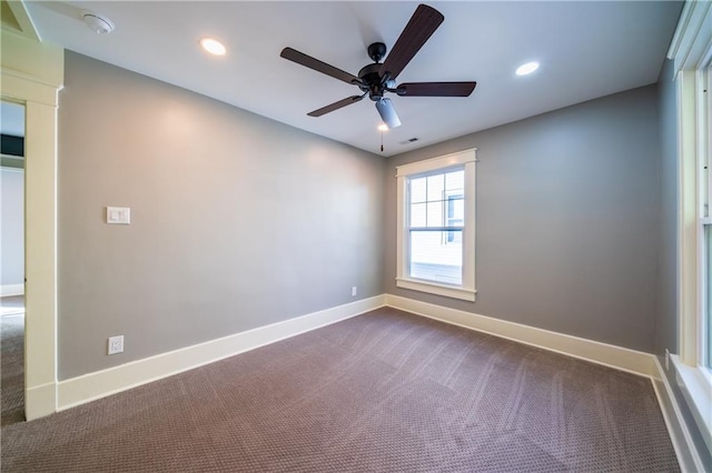 spare room featuring ceiling fan and dark colored carpet