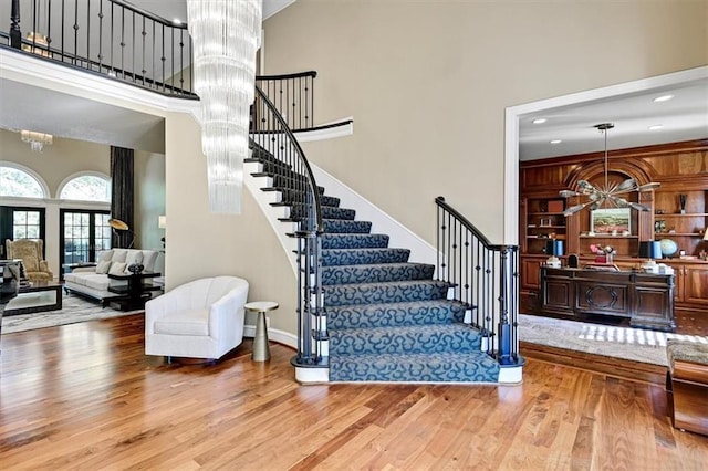 stairs with hardwood / wood-style flooring, an inviting chandelier, and a high ceiling