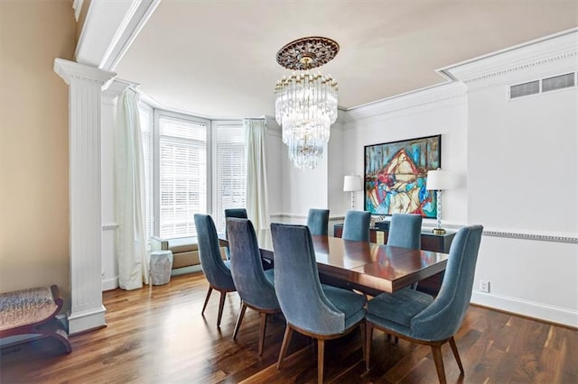 dining area featuring an inviting chandelier, ornamental molding, dark wood-type flooring, and ornate columns