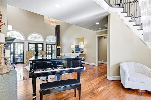 misc room with an inviting chandelier, french doors, and wood-type flooring