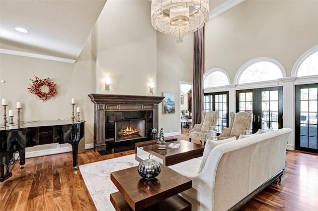 living room featuring dark wood-type flooring, crown molding, a fireplace, and a towering ceiling