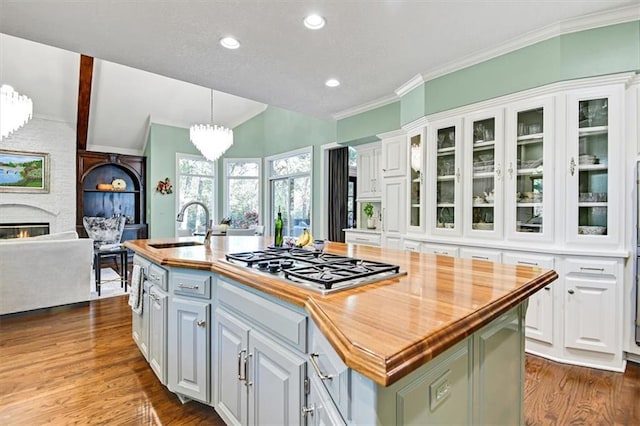 kitchen featuring stainless steel gas cooktop, a center island with sink, sink, white cabinetry, and dark hardwood / wood-style flooring