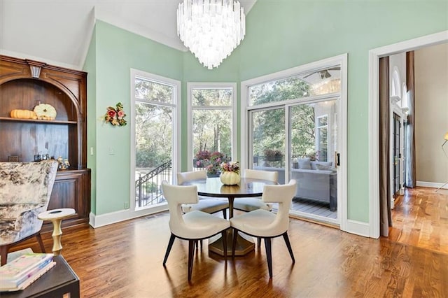 dining space with a towering ceiling, an inviting chandelier, and hardwood / wood-style floors