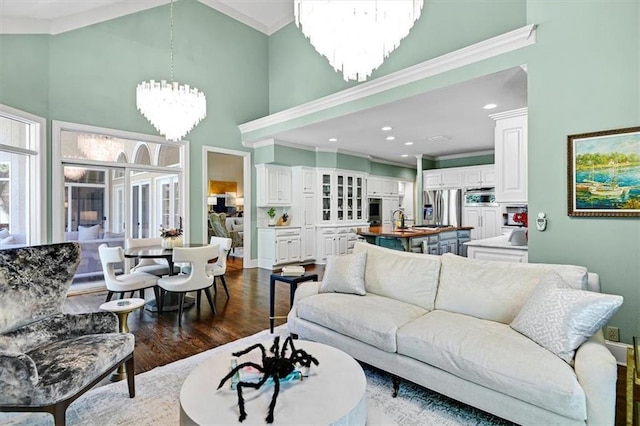 living room featuring ornamental molding, a high ceiling, hardwood / wood-style flooring, and a chandelier