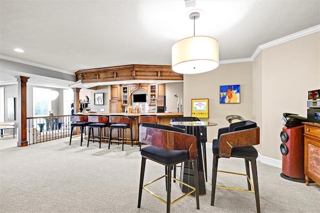 dining room featuring ornamental molding, decorative columns, and light carpet