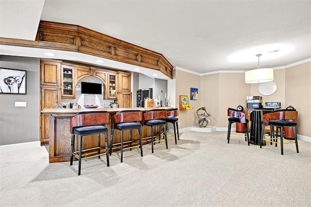 kitchen with light carpet, ornamental molding, decorative light fixtures, and a kitchen breakfast bar