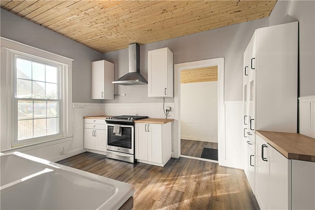 kitchen featuring wall chimney exhaust hood, wood ceiling, stainless steel gas range, white cabinetry, and butcher block counters