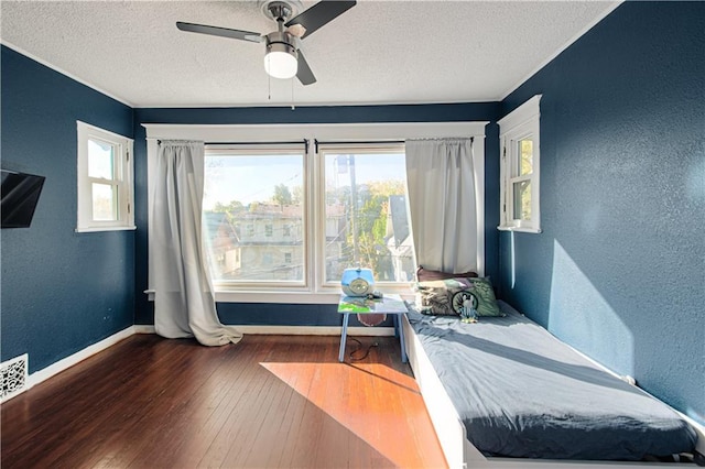 bedroom featuring ceiling fan, dark hardwood / wood-style floors, and a textured ceiling