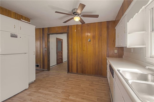 kitchen with white cabinets, white fridge, light hardwood / wood-style flooring, and sink