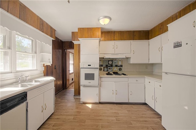 kitchen with decorative backsplash, white appliances, sink, light hardwood / wood-style flooring, and white cabinets