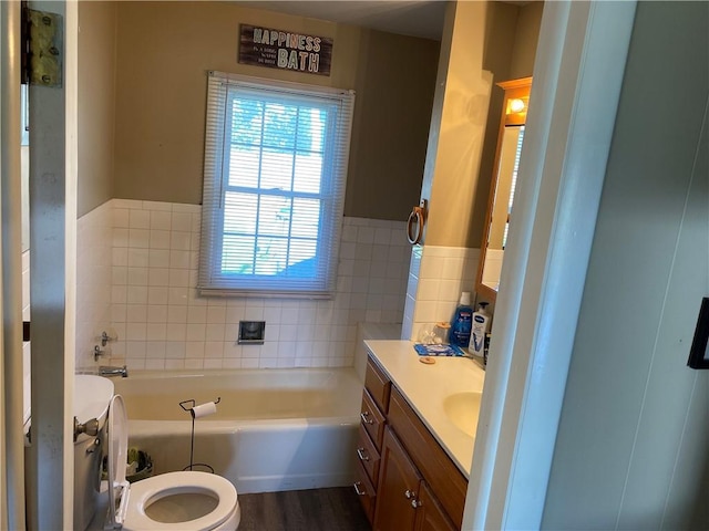 bathroom with hardwood / wood-style flooring, toilet, a bathtub, vanity, and tile walls