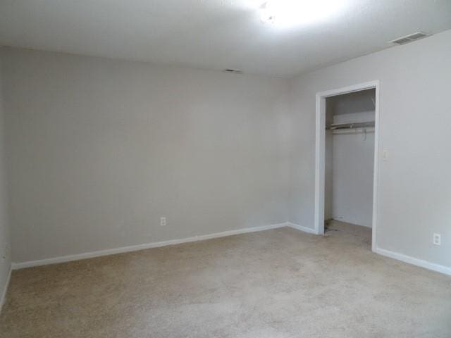 unfurnished bedroom with a closet and light colored carpet