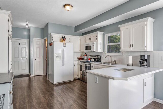 kitchen with backsplash, dark wood-type flooring, a sink, white appliances, and a peninsula