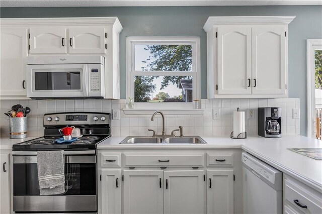 kitchen featuring white appliances, light countertops, a sink, and white cabinets