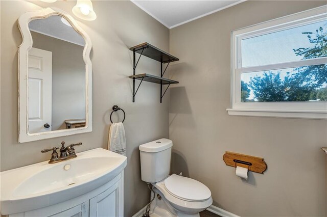 half bath with baseboards, vanity, and toilet