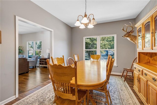 dining room with baseboards, wood finished floors, and an inviting chandelier