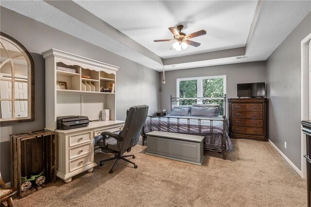 carpeted bedroom featuring a tray ceiling, a ceiling fan, and baseboards