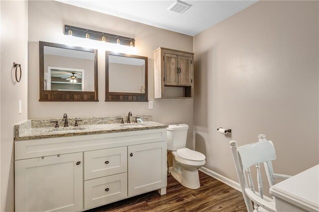 bathroom with toilet, visible vents, a sink, and wood finished floors