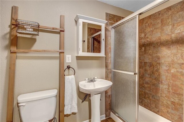 bathroom featuring toilet and a shower stall