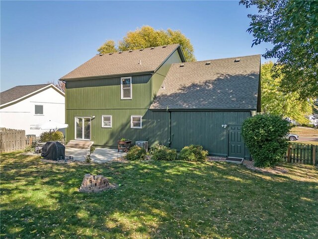 back of house with a patio, a yard, roof with shingles, and fence