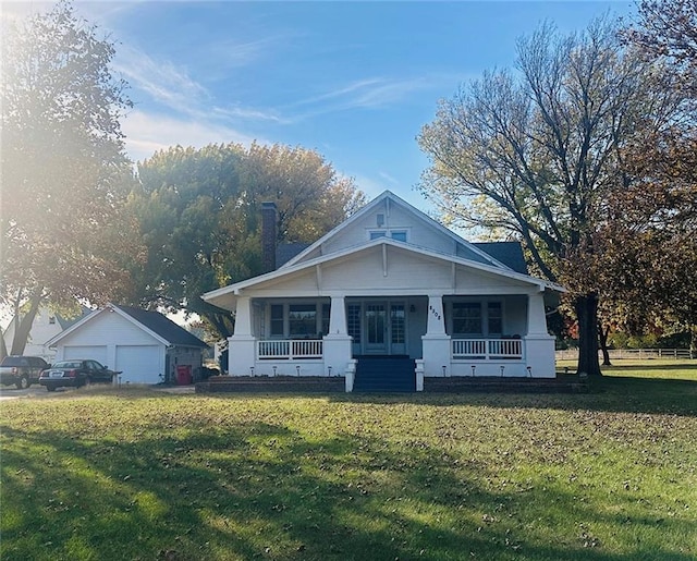 view of front of property featuring an outdoor structure, a garage, a front lawn, and a porch