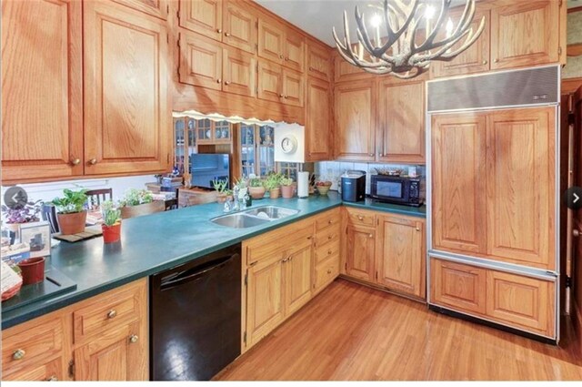 kitchen featuring an inviting chandelier, black appliances, pendant lighting, light hardwood / wood-style floors, and sink