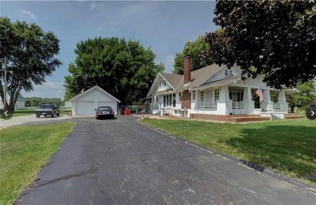 view of front of property featuring a front yard, a porch, an outbuilding, and a garage